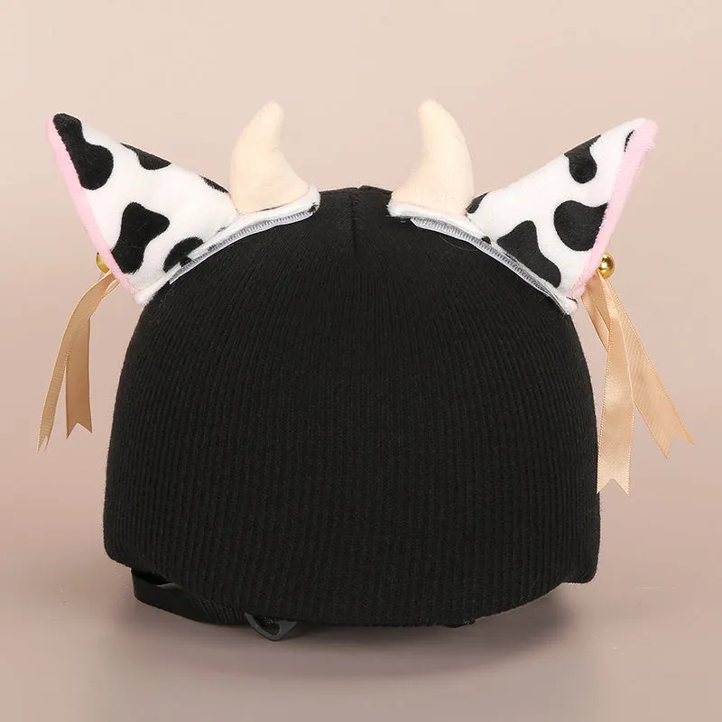 A plush fabric helmet cover with cartoon print and 3D ears, next to a matching beanie hat, on a neutral background.