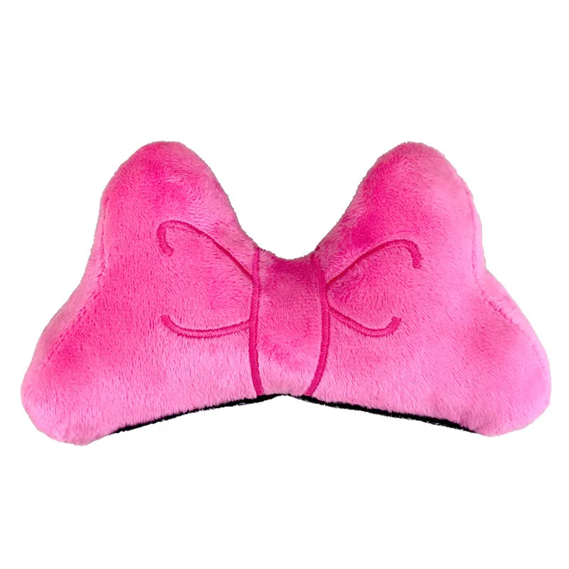 Close-up of a red plush bow decoration with a metal clip, shown next to a motorcycle helmet.