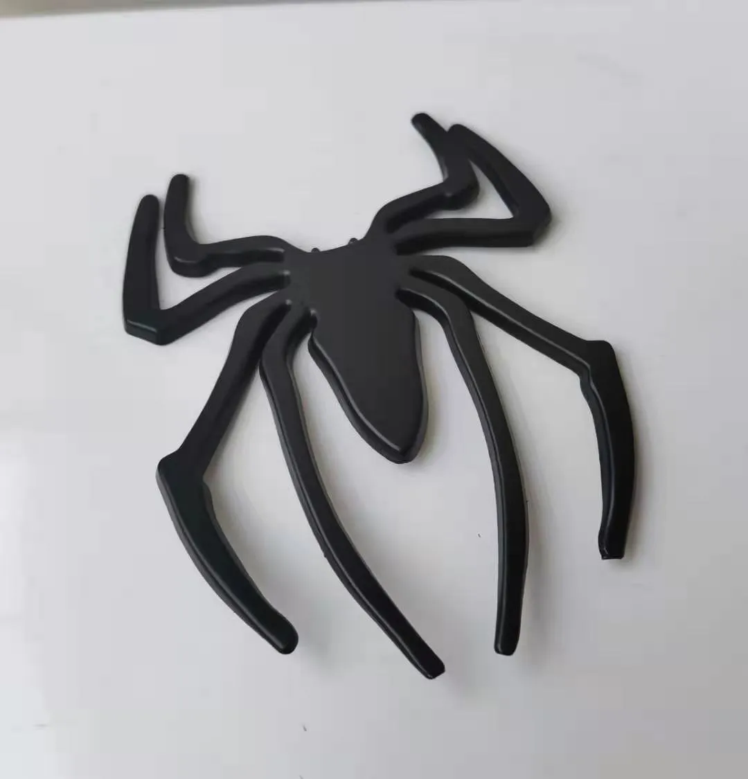 Three-dimensional metal spider bumper sticker in metallic finish measuring 7cm by 5cm
