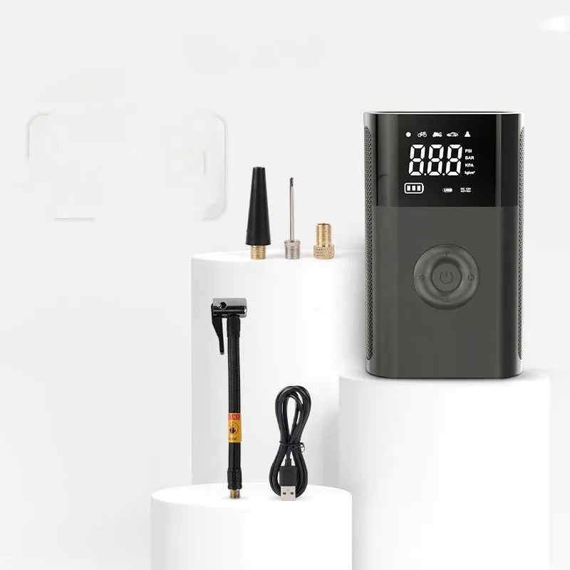 Black handheld wireless digital tyre inflator with LCD screen, LED light and multiple nozzle attachments on a table.