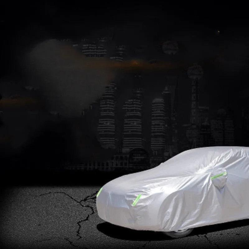 Silver-coated black taffeta universal car cover fitted over a sedan in outdoor parking