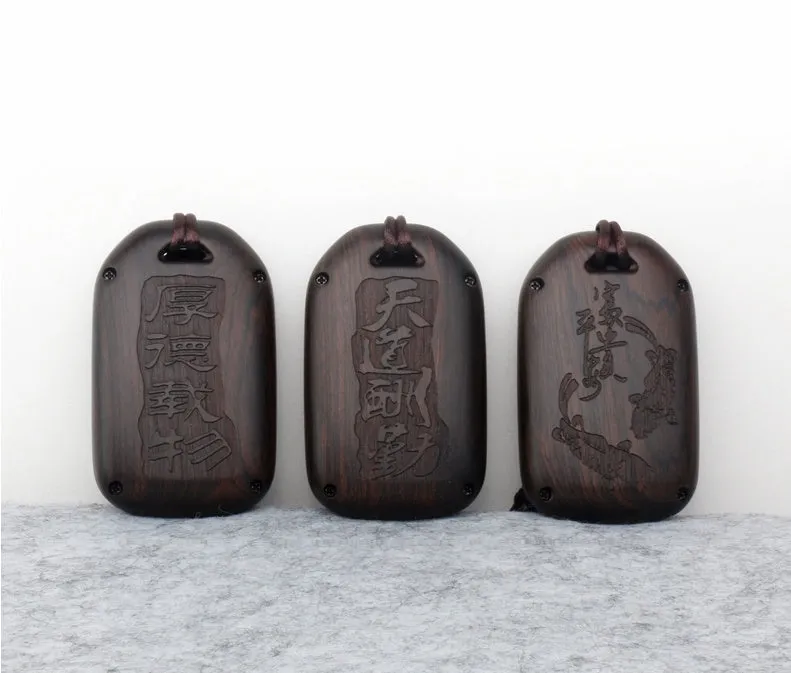 Solid ebony sandalwood key case with key rings, showing carved wood grain on a plain background