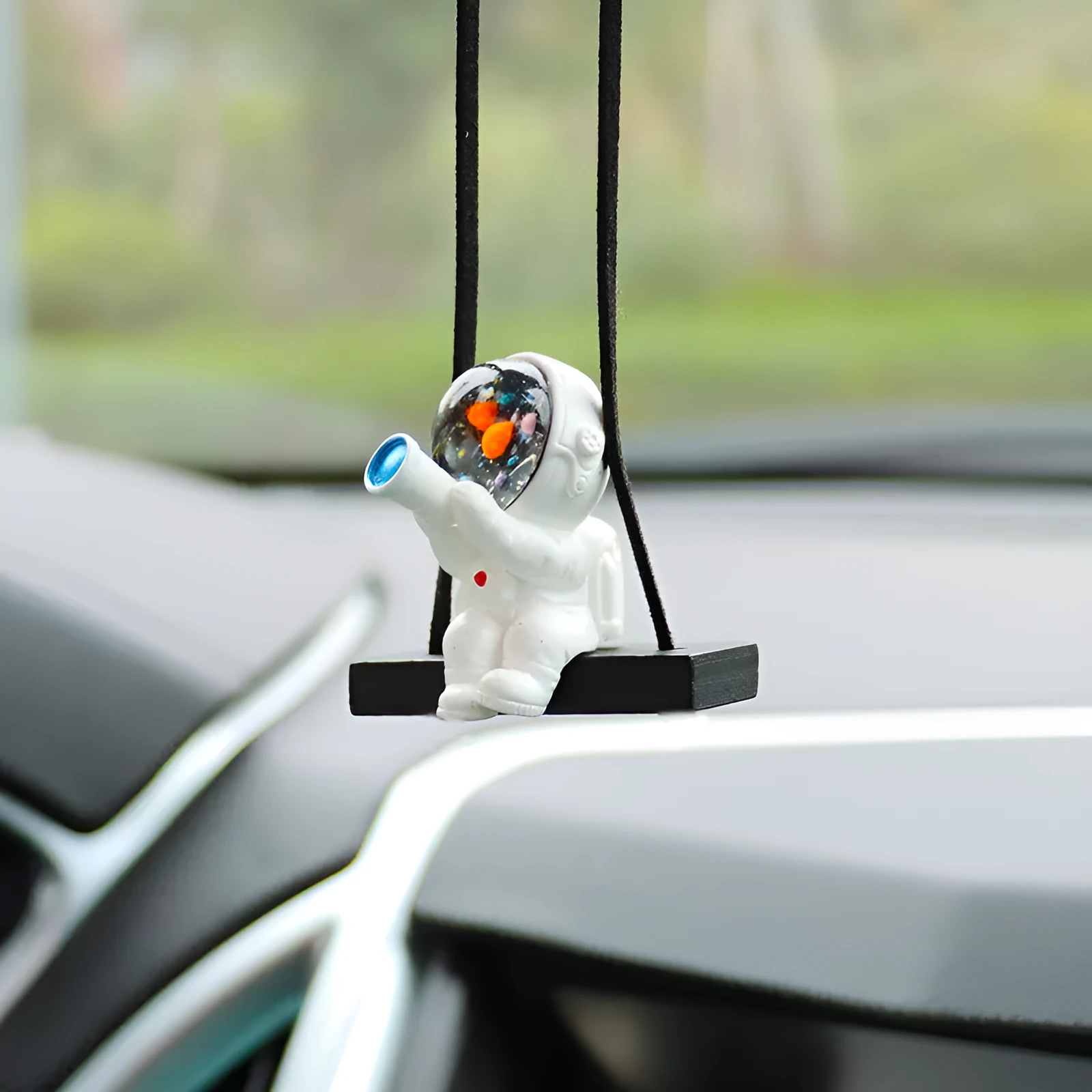 Resin astronaut car pendant showing cartoon astronaut designs including telescope, red flag, and radish variations