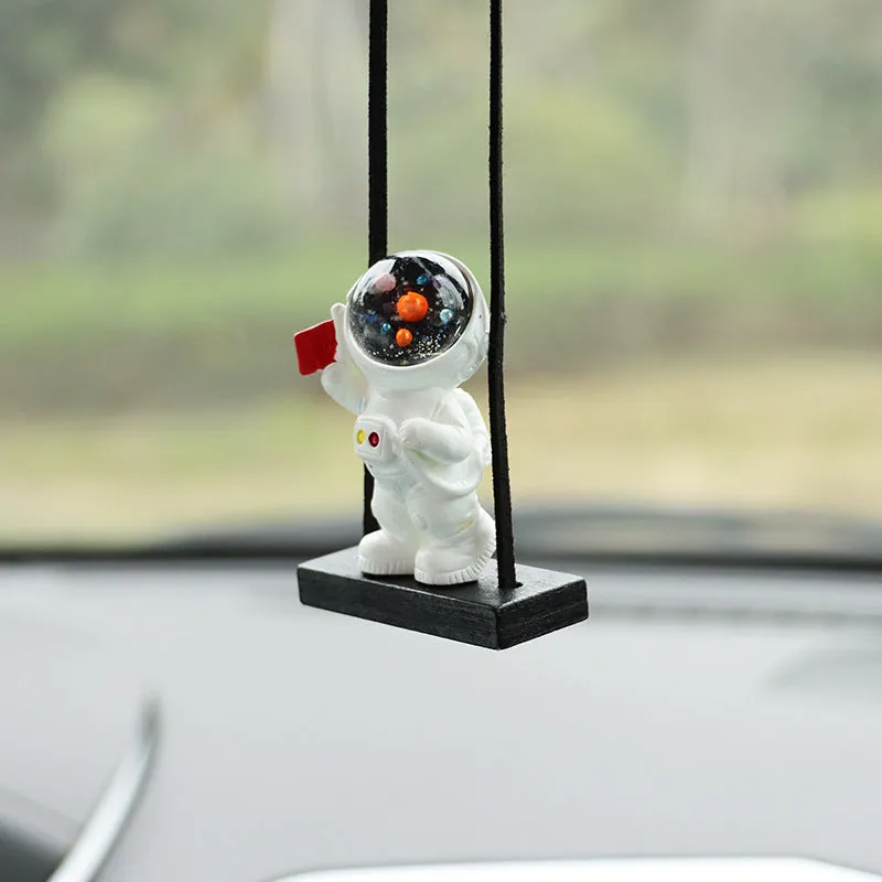 Resin astronaut car pendant showing cartoon astronaut designs including telescope, red flag, and radish variations