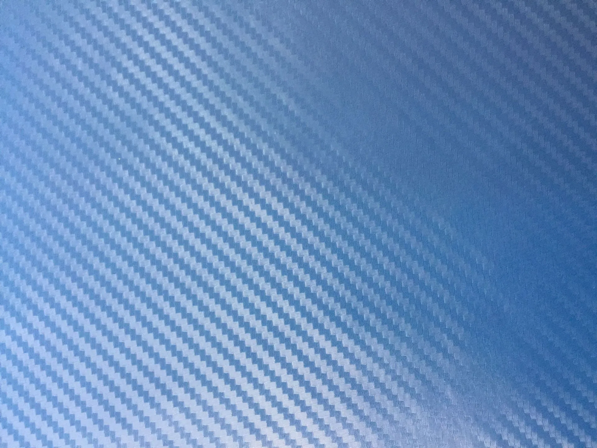 3D carbon fibre car sticker roll in black with textured pattern on a white background