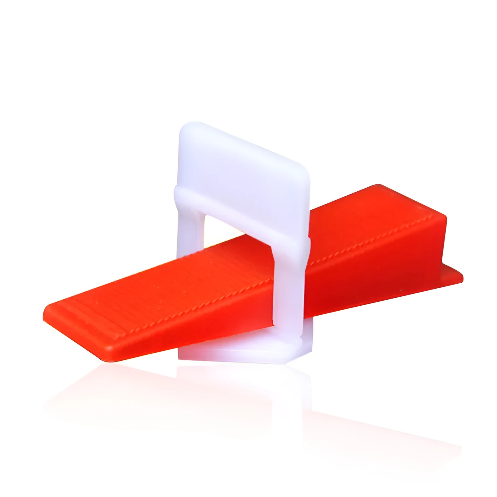 Orange plastic tile leveling wedges and white base clips on a tiled floor, with a rubber hammer nearby
