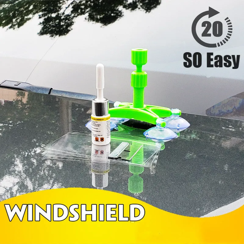 Windshield repair fluid kit with green resin, repair device, curing strips, and sleeved razor blade on a car windscreen