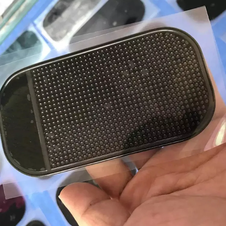Black silicone car anti slip mat with spider-web texture, 13x7cm, on a car dashboard holding a smartphone