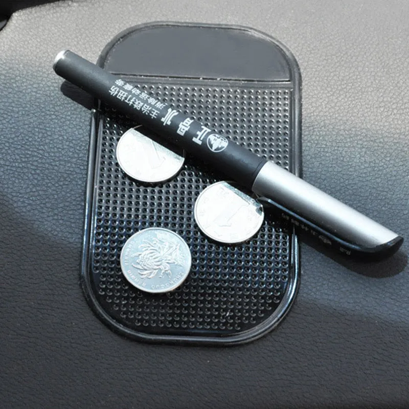 Black silicone car anti slip mat with spider-web texture, 13x7cm, on a car dashboard holding a smartphone