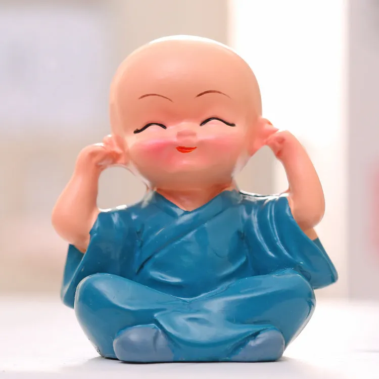 Set of 4 miniature resin Buddha monk statues in blue, brown, gray, and orange, 4.7 cm tall, on a shelf