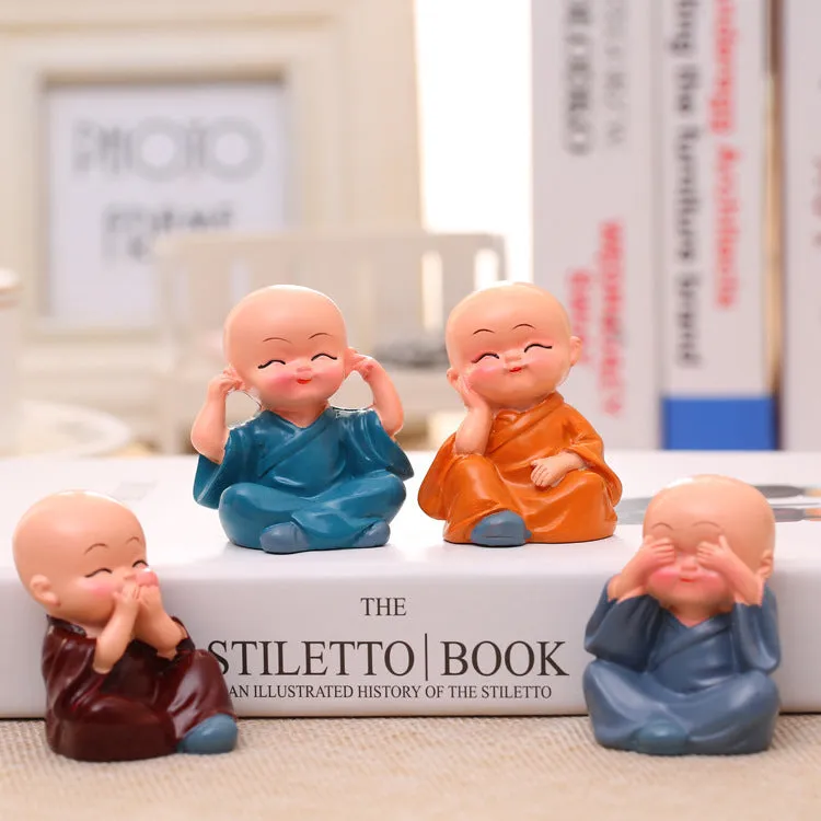 Set of 4 miniature resin Buddha monk statues in blue, brown, gray, and orange, 4.7 cm tall, on a shelf