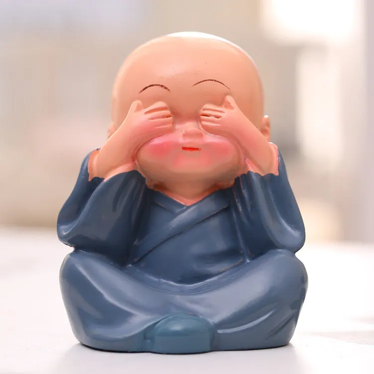 Set of 4 miniature resin Buddha monk statues in blue, brown, gray, and orange, 4.7 cm tall, on a shelf