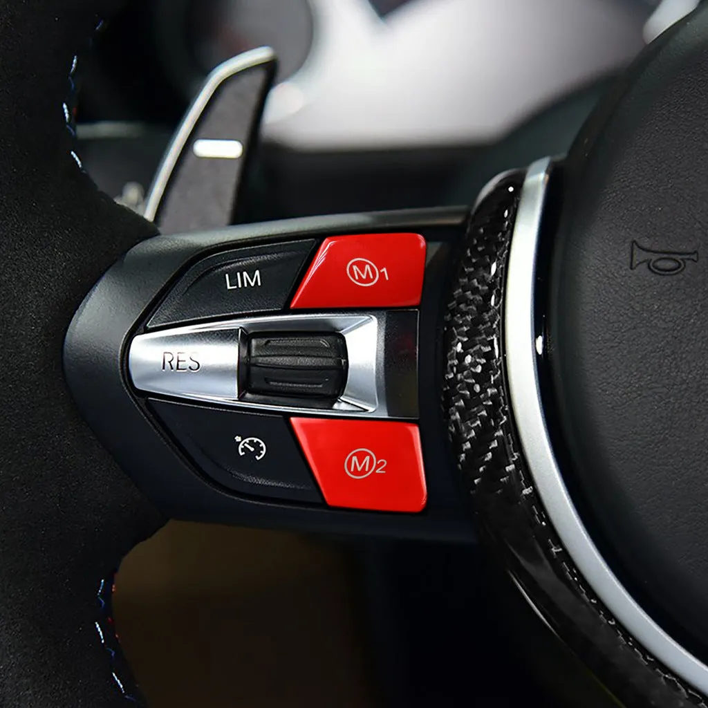 Pair of red and blue BMW M1 M2 steering wheel mode buttons on a dark background.