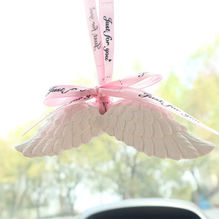 Angel wings gypsum car perfume pendant with black ribbon and white wings hanging from a rearview mirror
