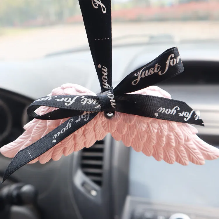 Angel wings gypsum car perfume pendant with black ribbon and white wings hanging from a rearview mirror