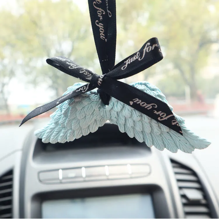 Angel wings gypsum car perfume pendant with black ribbon and white wings hanging from a rearview mirror
