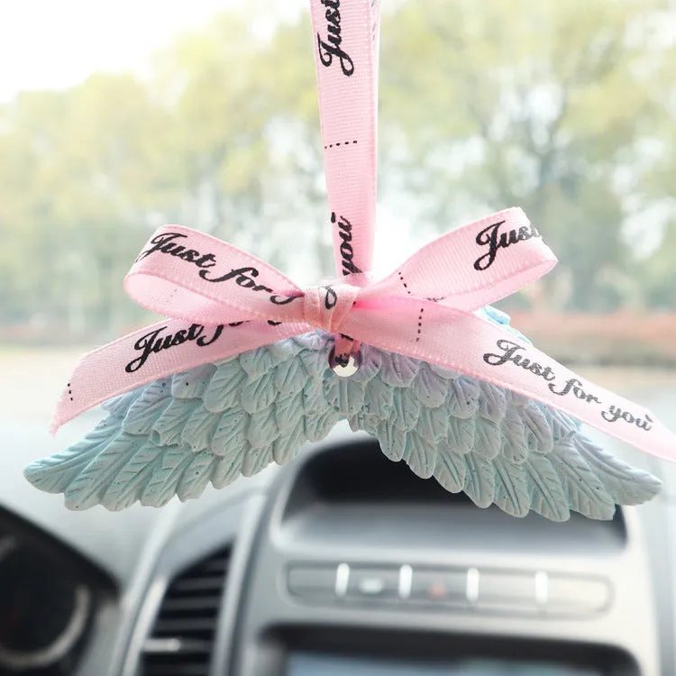 Angel wings gypsum car perfume pendant with black ribbon and white wings hanging from a rearview mirror