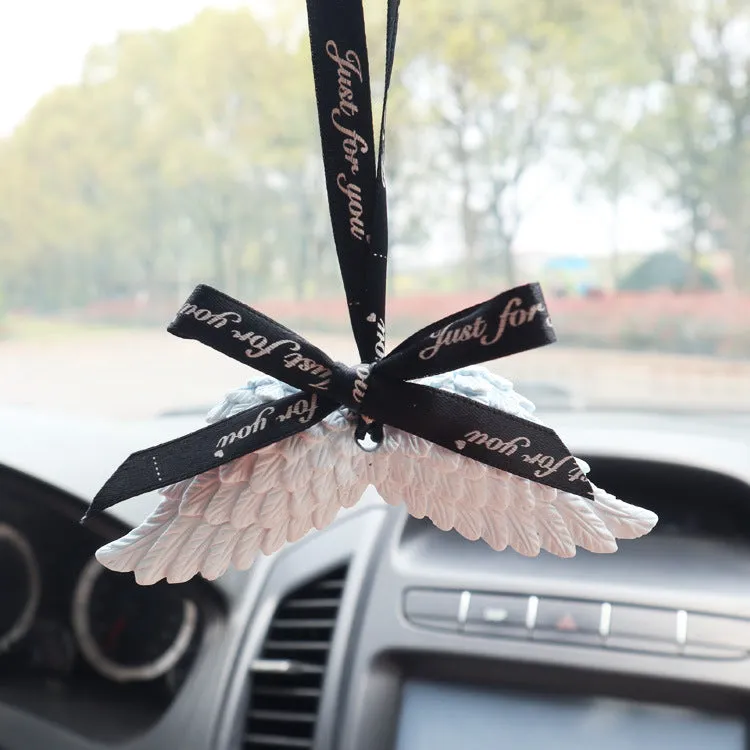 Angel wings gypsum car perfume pendant with black ribbon and white wings hanging from a rearview mirror