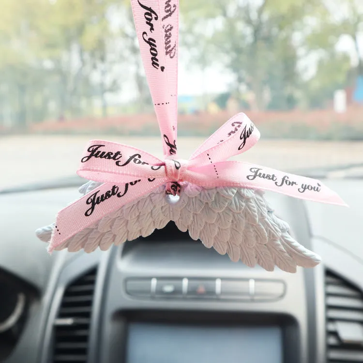 Angel wings gypsum car perfume pendant with black ribbon and white wings hanging from a rearview mirror
