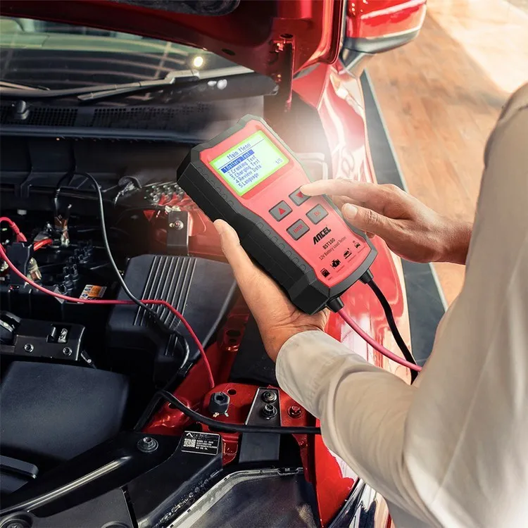 Red car battery tester 12V diagnostic tool with display and cables on white background