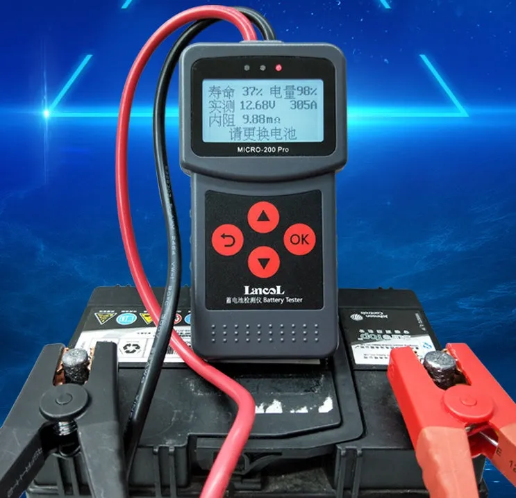 Black car battery tester with digital display measuring internal resistance on a workbench