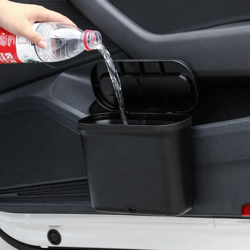 Black 1.7L PP plastic car trash can suspended on centre console with lid open, interior visible