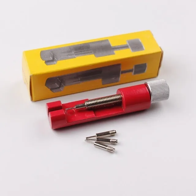 Watch strap link remover tool in black with two thimbles and a metal watch band placed on the detacher groove