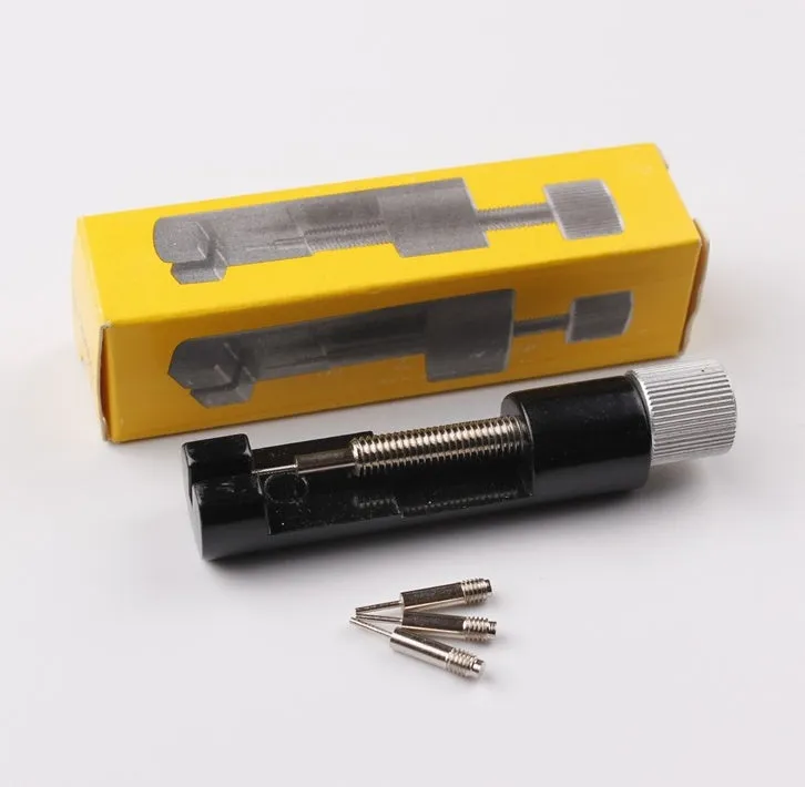 Watch strap link remover tool in black with two thimbles and a metal watch band placed on the detacher groove