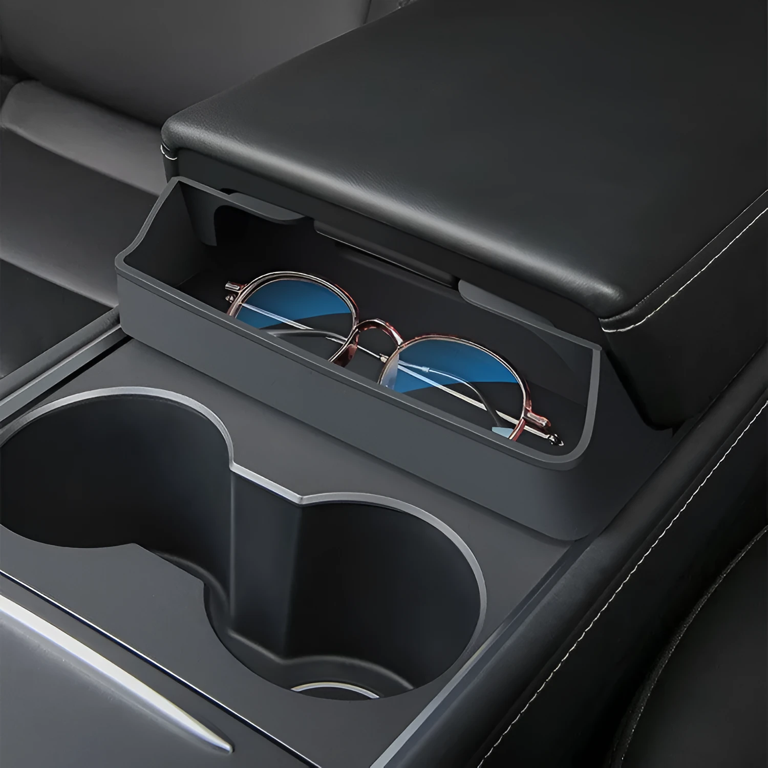 Black silicone sunglasses holder installed in Tesla centre console armrest compartment