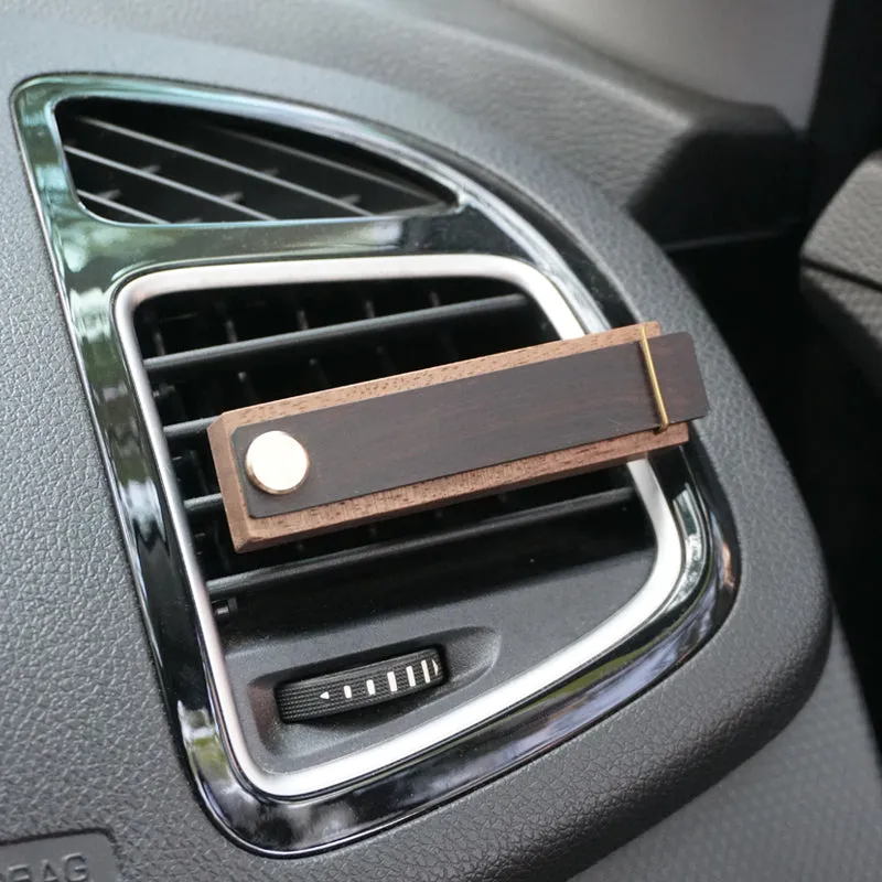 Customisable car perfume ornament diffuser with wood body and brass clip on a car air vent