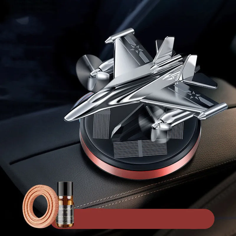 Solar powered rotating silver fighter jet car air freshener ornament on a dashboard.