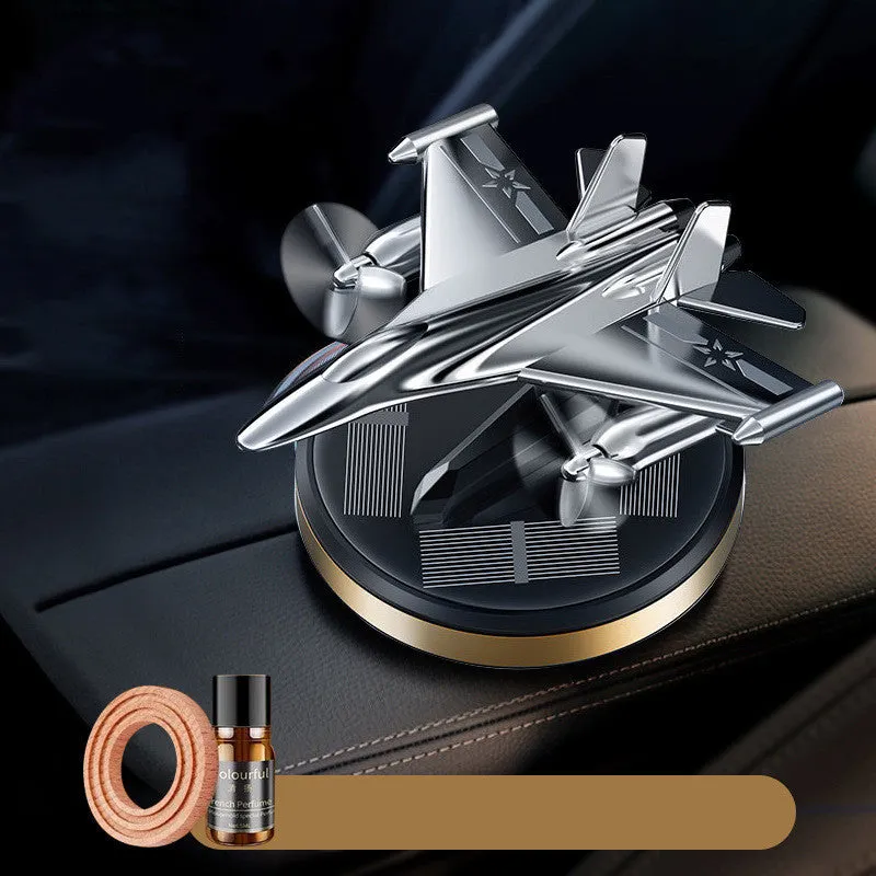 Solar powered rotating silver fighter jet car air freshener ornament on a dashboard.