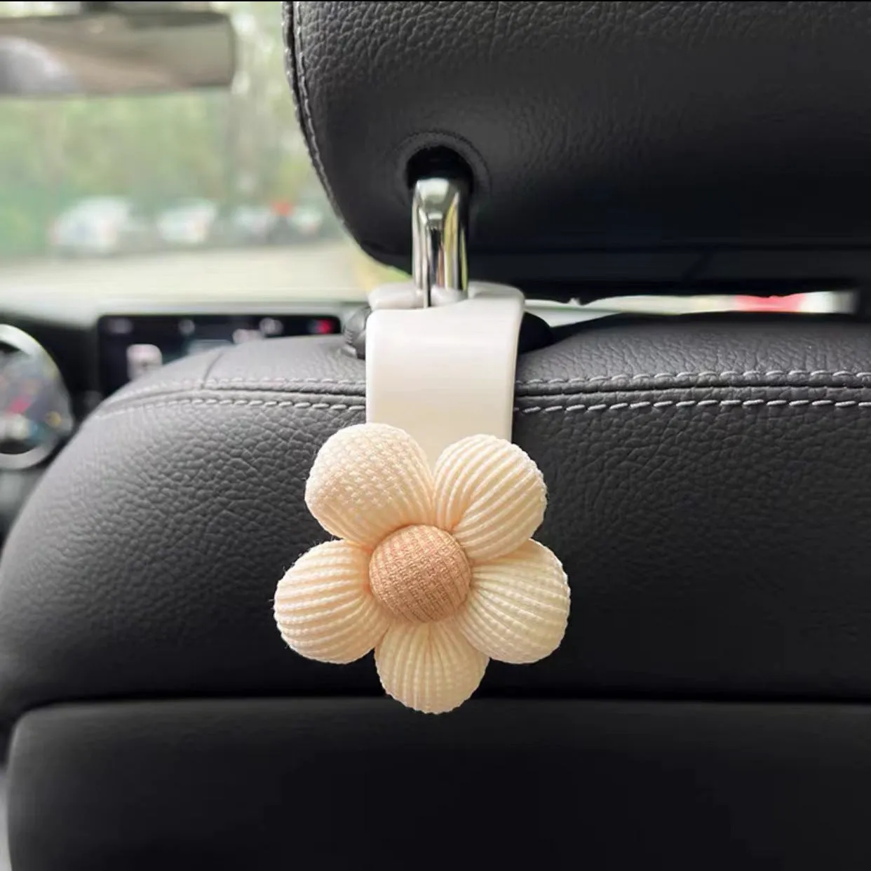 Plastic car seat hook in white, 11 by 5.5 cm, hanging from a headrest