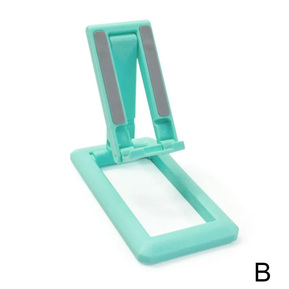 A folded and unfolded view of a black retractable mobile phone desktop stand on a wooden desk.