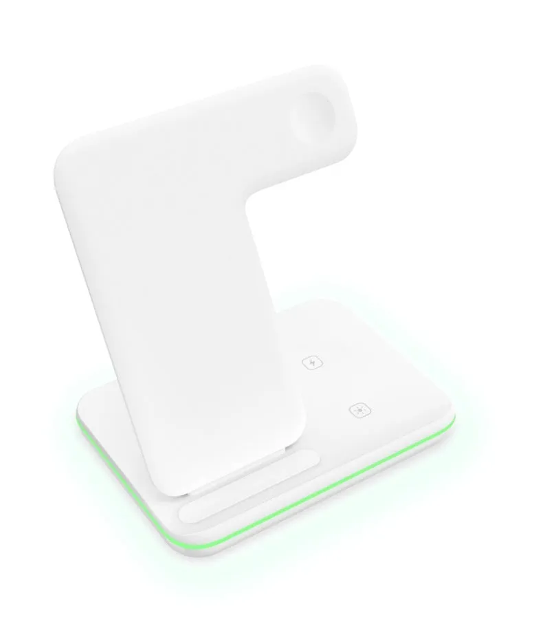 A white three-in-one wireless charging stand on a desk, charging a mobile phone, a smartwatch, and a pair of wireless headphones.
