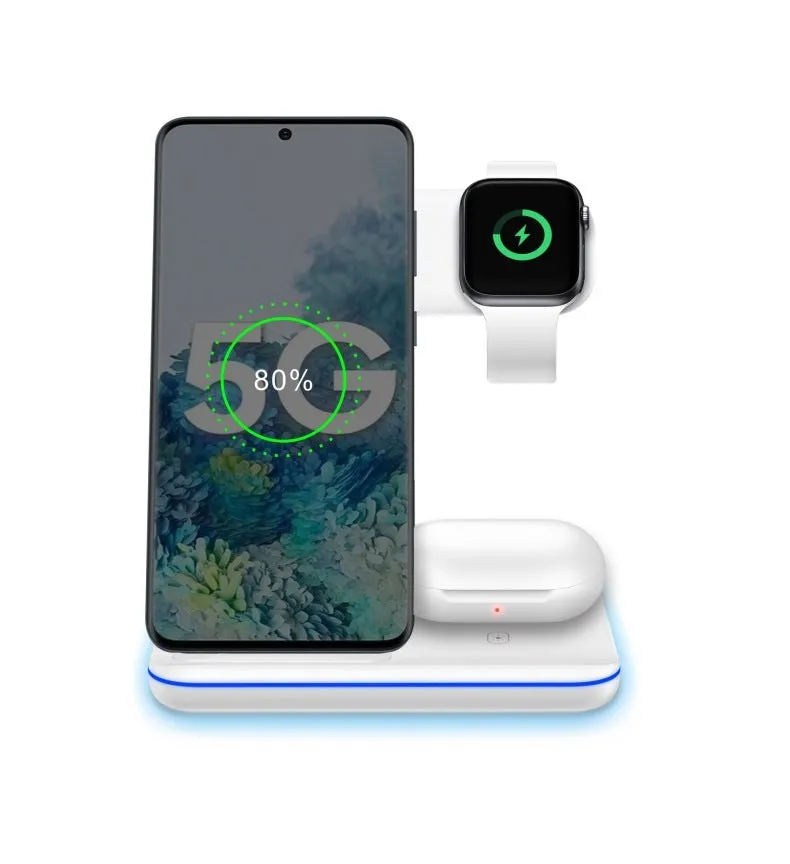 A white three-in-one wireless charging stand on a desk, charging a mobile phone, a smartwatch, and a pair of wireless headphones.