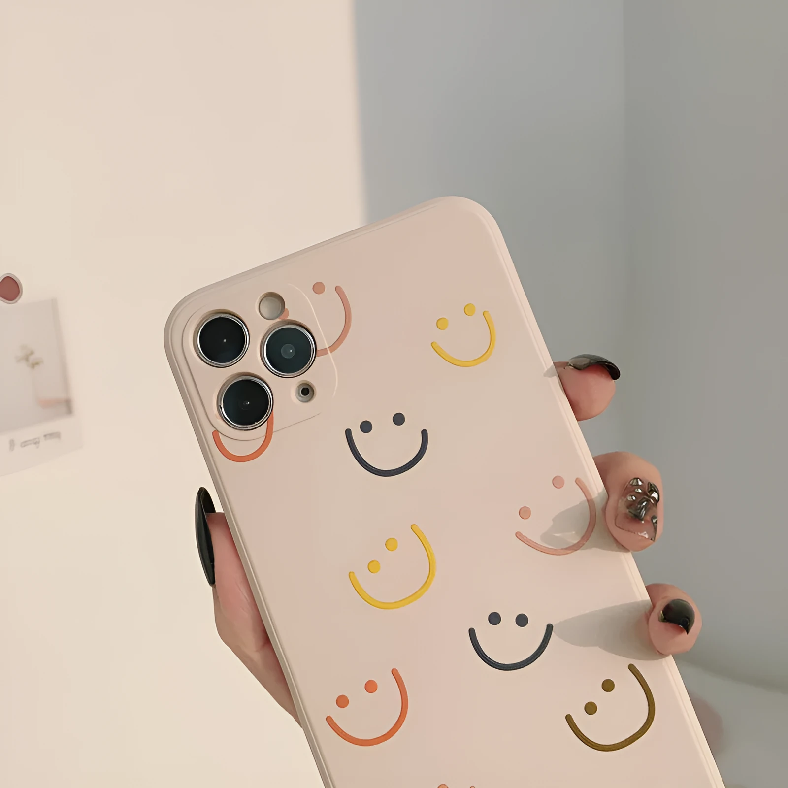 Simple silicone TPU iPhone case with a painted smiley face design on a solid colour background.