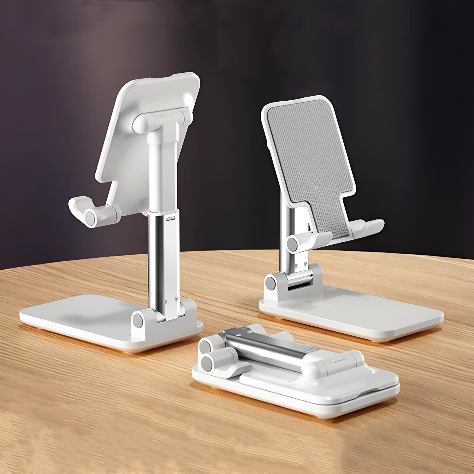 Folding telescopic mobile phone bracket in white, blue, green, or pink colours on a desktop.