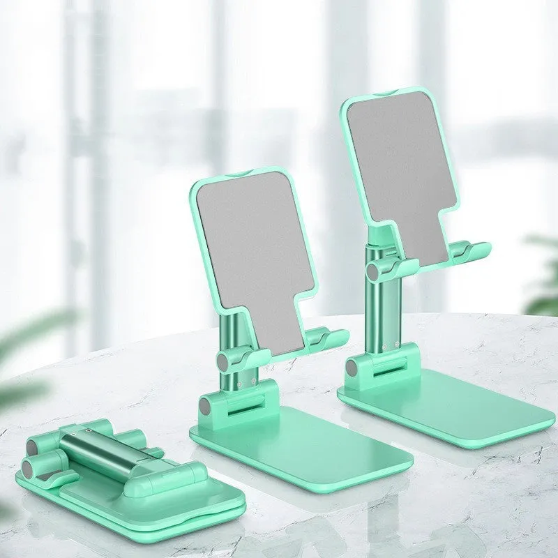 Folding telescopic mobile phone bracket in white, blue, green, or pink colours on a desktop.