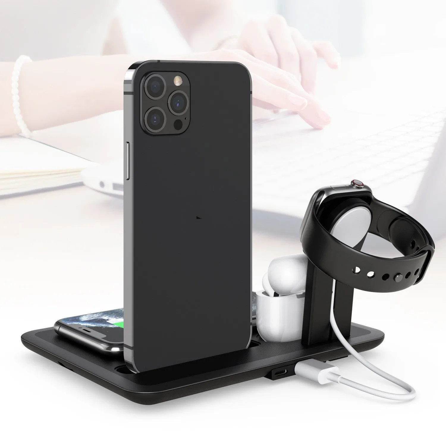 Black multi-device wireless charging stand holding a phone, headphones, and a smartwatch on a desk.