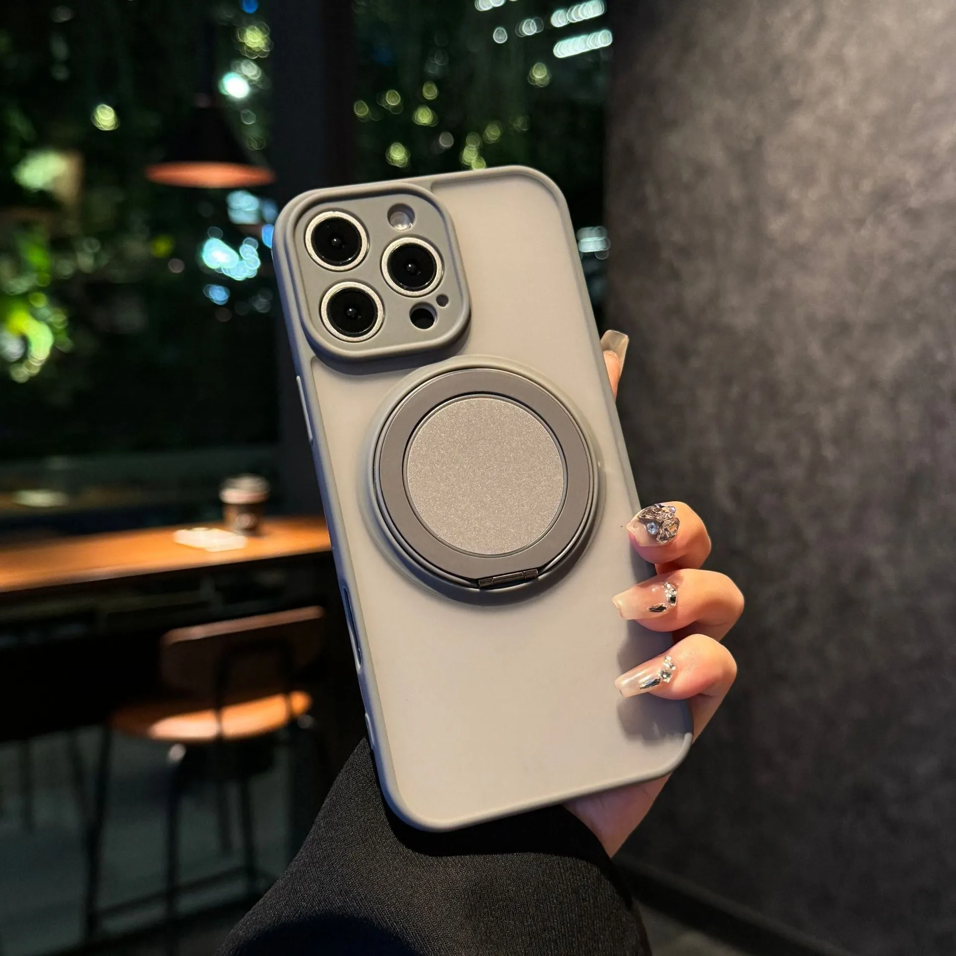 Black frosted phone case for iPhone 17 with a rotating kickstand extended and visible magnetic ring on the back.