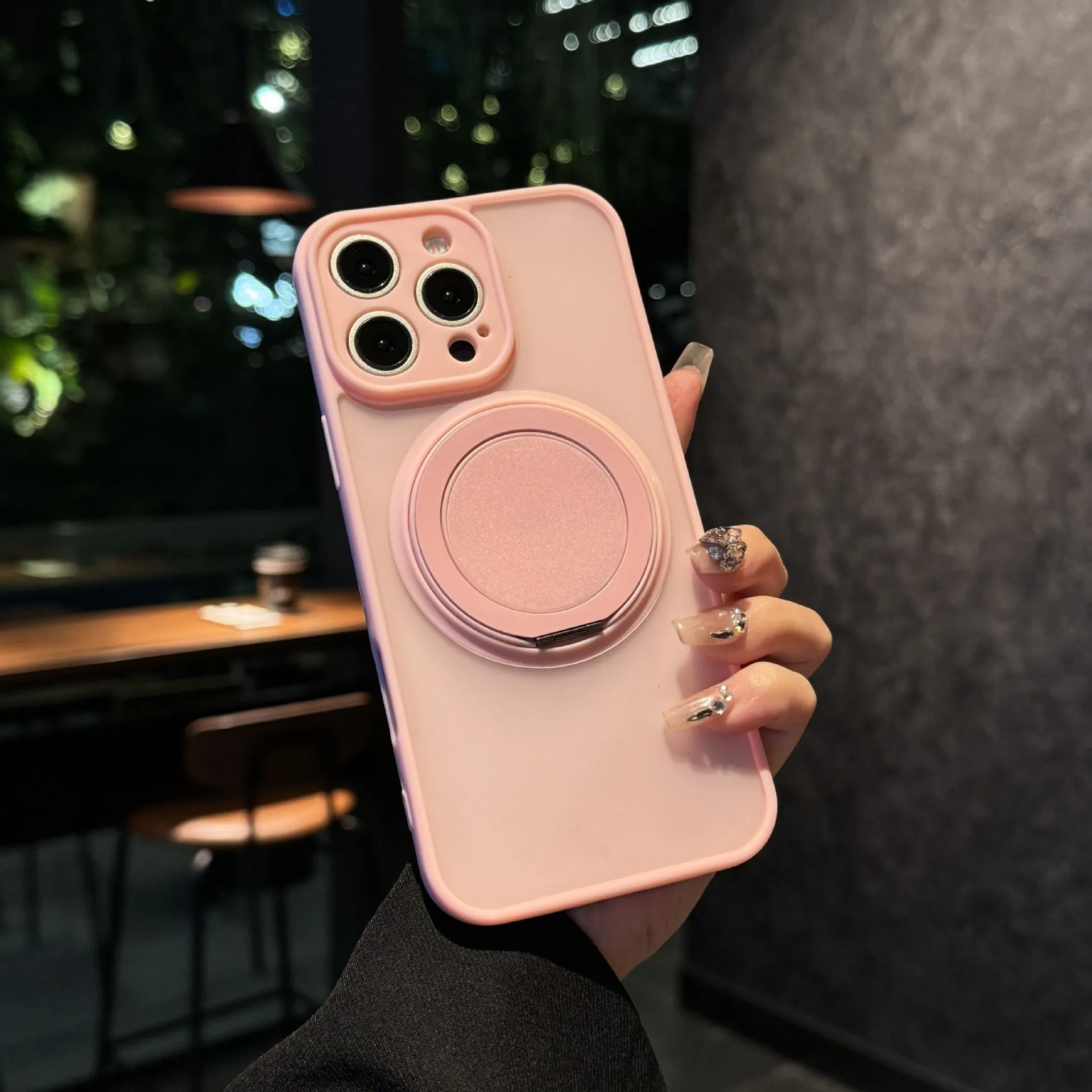 Black frosted phone case for iPhone 17 with a rotating kickstand extended and visible magnetic ring on the back.