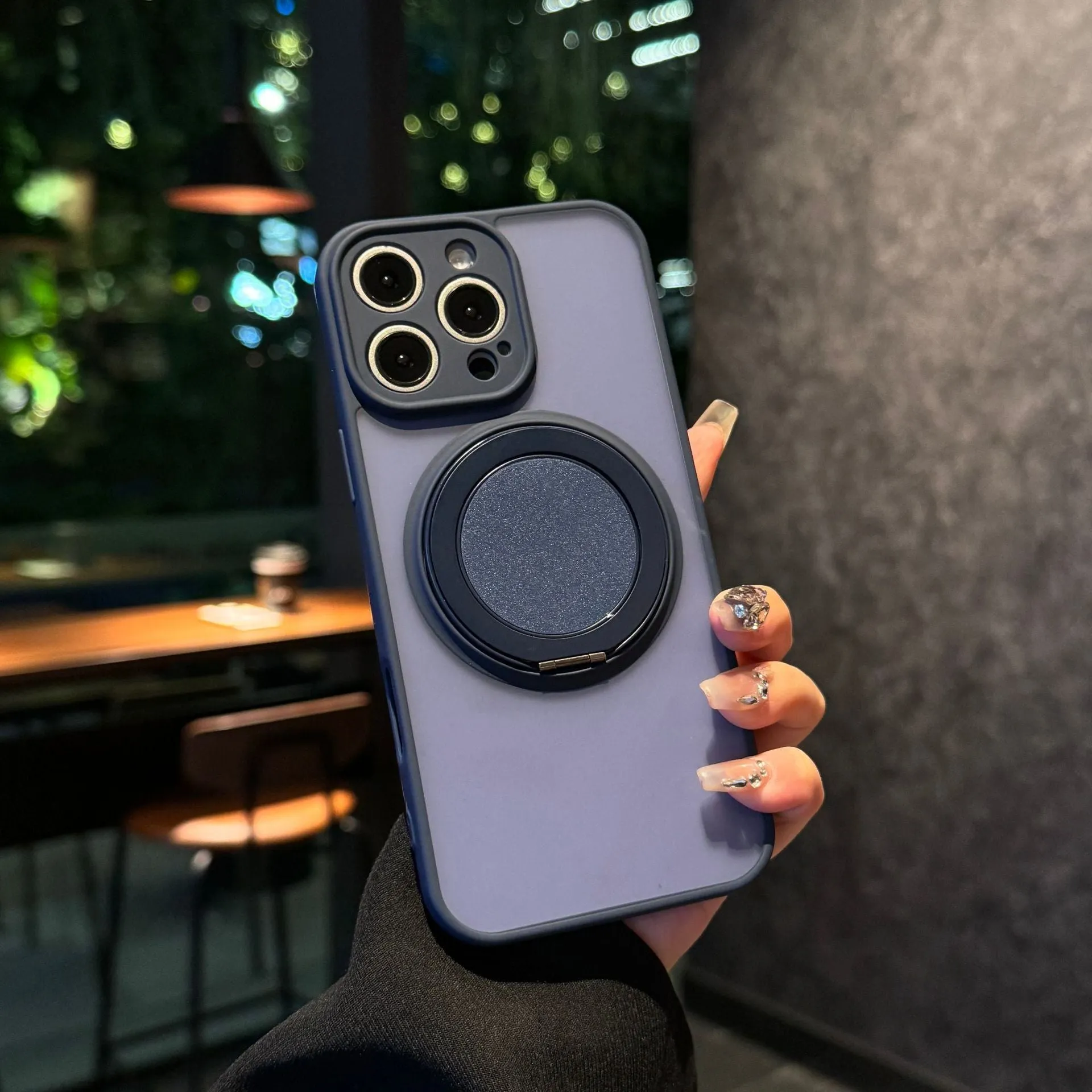 Black frosted phone case for iPhone 17 with a rotating kickstand extended and visible magnetic ring on the back.
