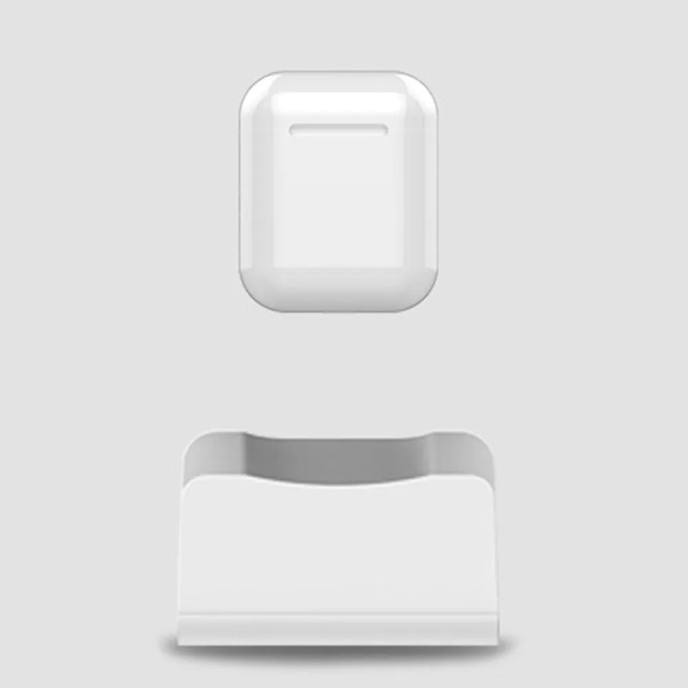 White headphone charging base station on a desk, holding a pair of over-ear headphones.