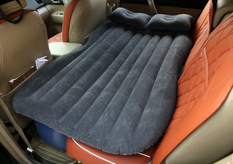 Inflatable car bed with flocked surface folded beside two pillows in storage bag for vehicle sleeping