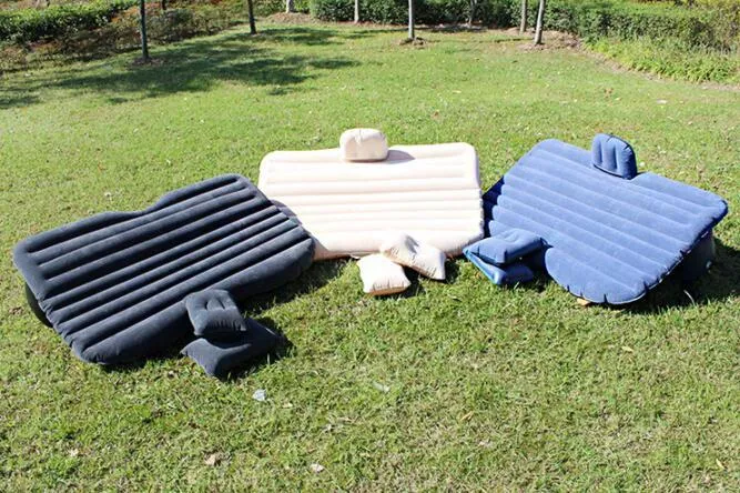 Inflatable car bed with flocked surface folded beside two pillows in storage bag for vehicle sleeping