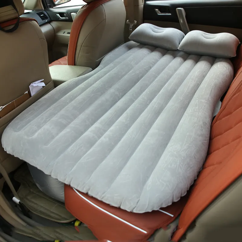 Inflatable car bed with flocked surface folded beside two pillows in storage bag for vehicle sleeping