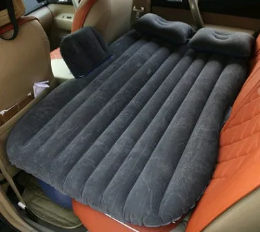 Inflatable car bed with flocked surface folded beside two pillows in storage bag for vehicle sleeping