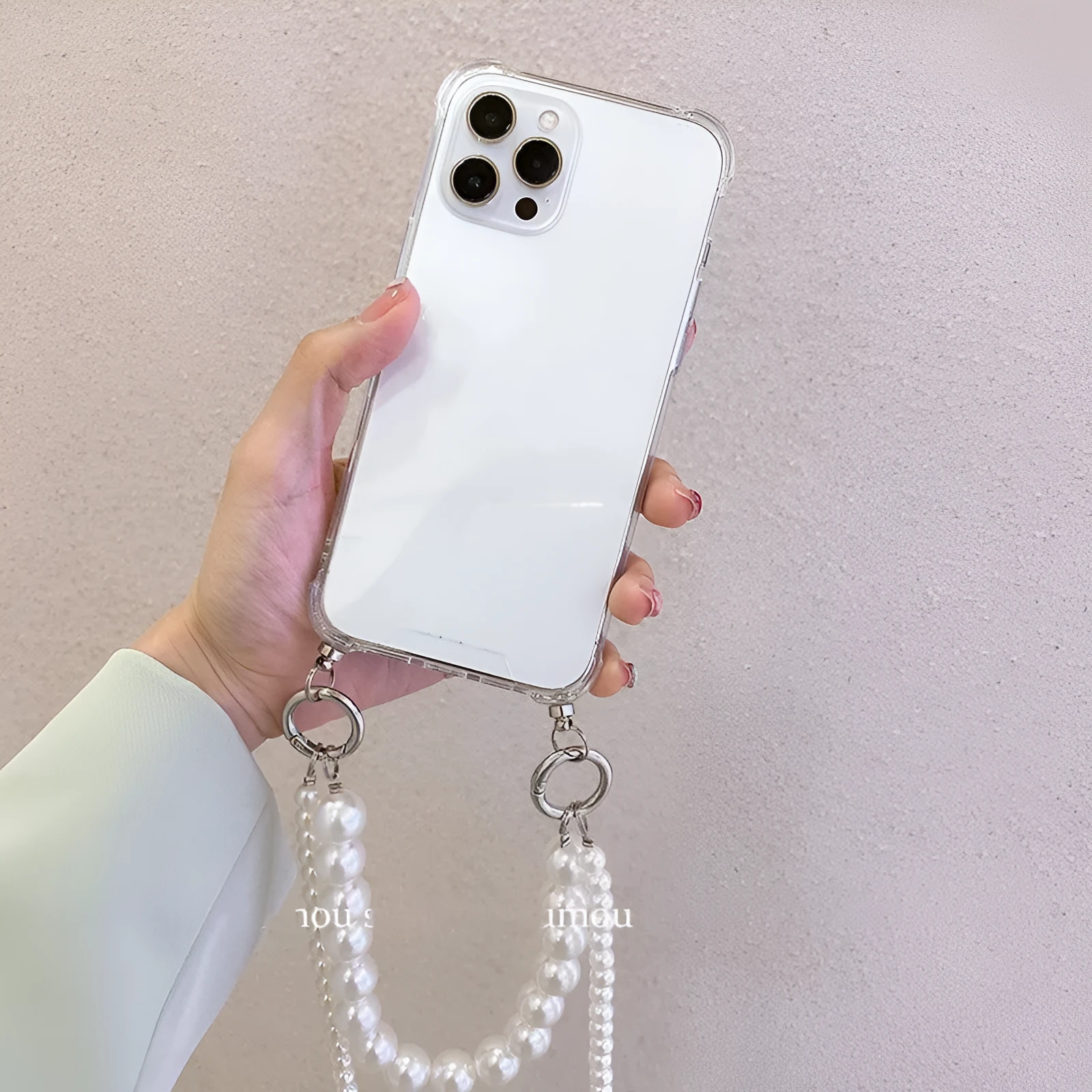 Soft Apple iPhone case with a large white pearl decoration and a silver chain attached.