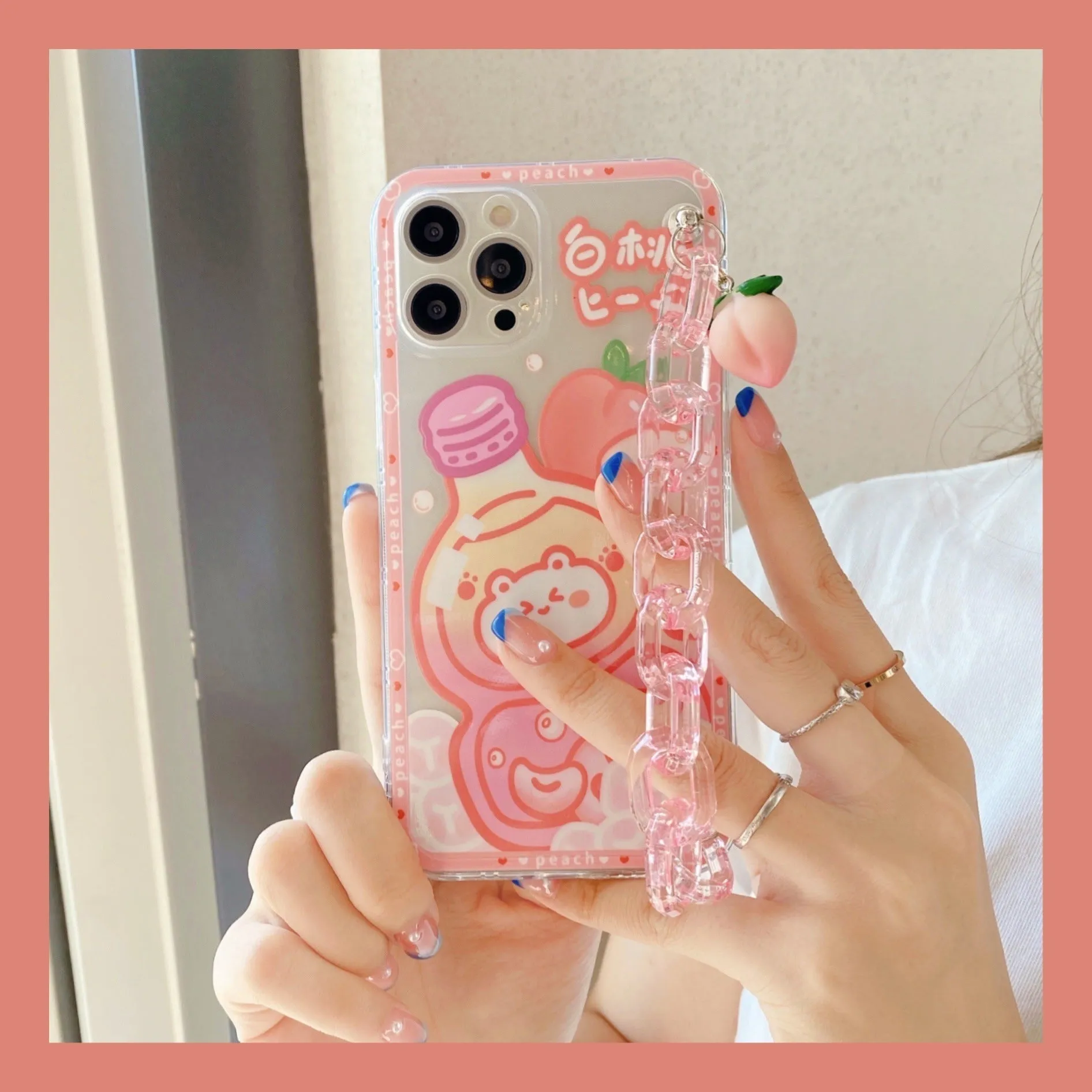 White silicone iPhone case with cartoon peach juice drink and bear design, shown with attached wrist strap.